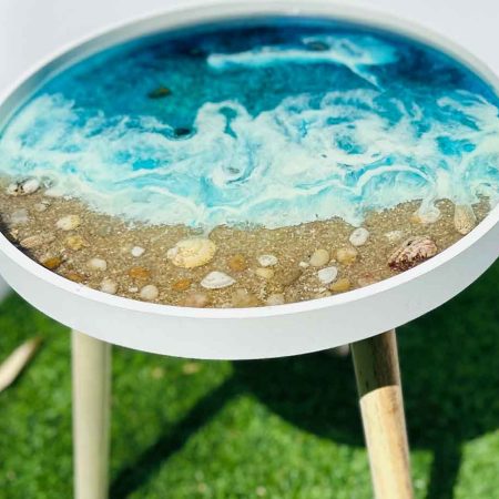 Mesa marina translúcida con detalles de arena y piedras naturales con fondo azulado