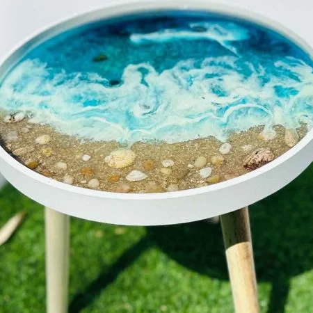 Mesa marina translúcida con detalles de arena y piedras naturales con fondo azulado